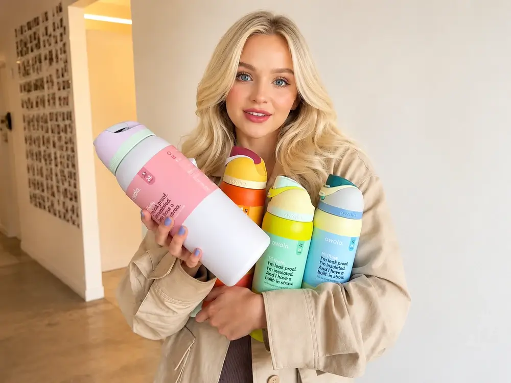 Woman holding four colorful Owala FreeSip water bottles, including pink, orange, green and blue designs in multiple sizes.