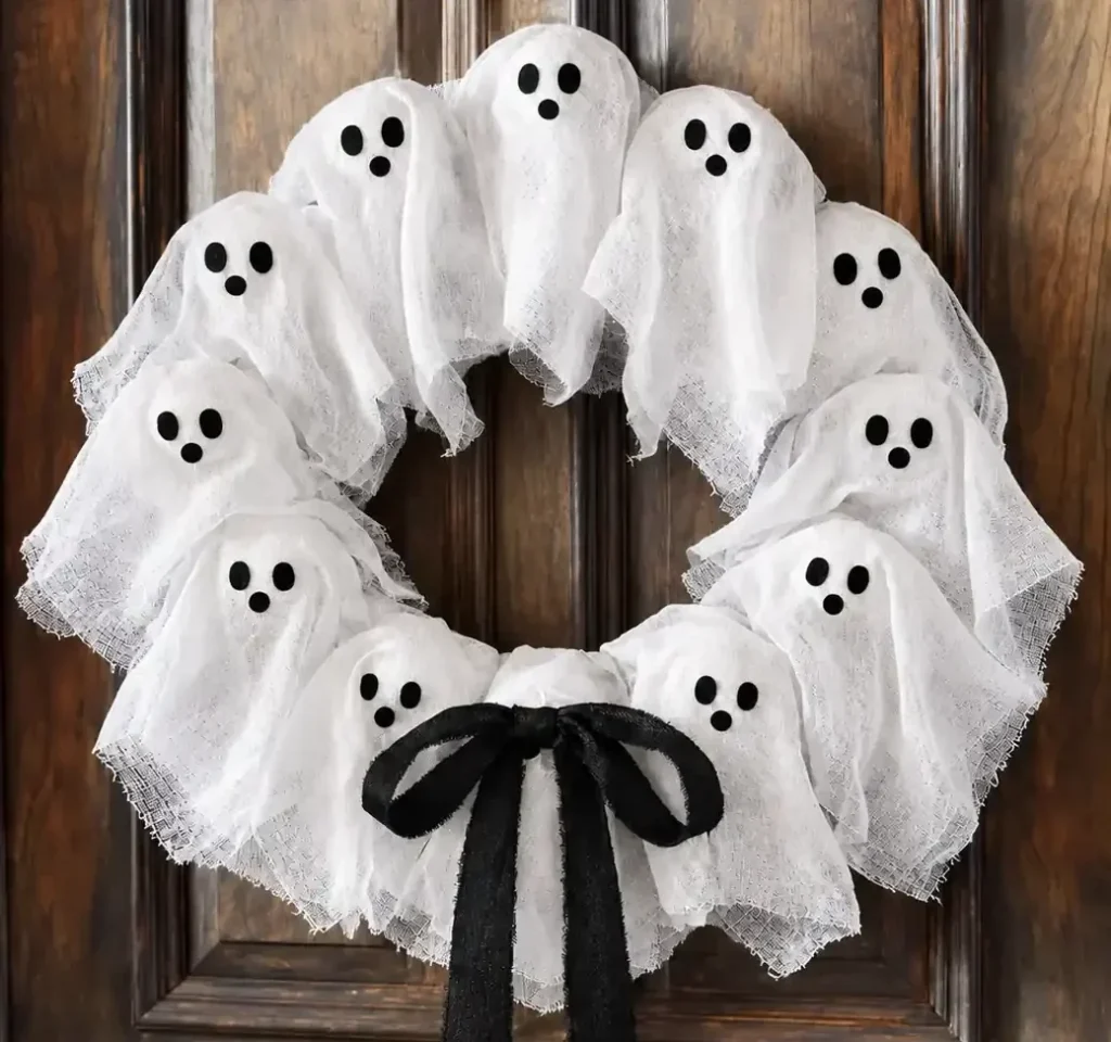 Halloween wreath ideas for a spooky front door, featuring a white ghost wreath with a black bow on a dark wooden door.