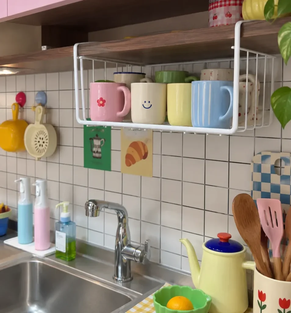 Under-shelf mug storage basket holding colorful coffee mugs in a kitchen