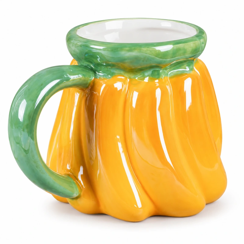 Yellow pumpkin-shaped ceramic mug with green rim and curved green handle.
